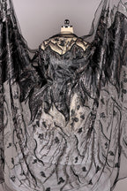 a black and white dress with intricate, shimmering embroidery and a flowing, draped cape-like garment.