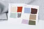 two pieces of paper with fabric swatches and QR codes, placed on a white surface.