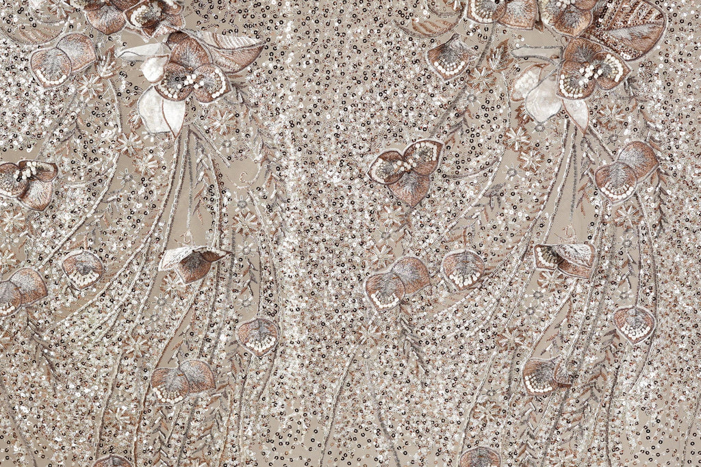 a close-up view of a fabric with a floral pattern, including various types of flowers and leaves. The fabric appears to be made of a shiny, sequined material, giving it a decorative and elegant appearance.