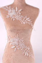 A mannequin torso with delicate white lace floral embroidery on it.