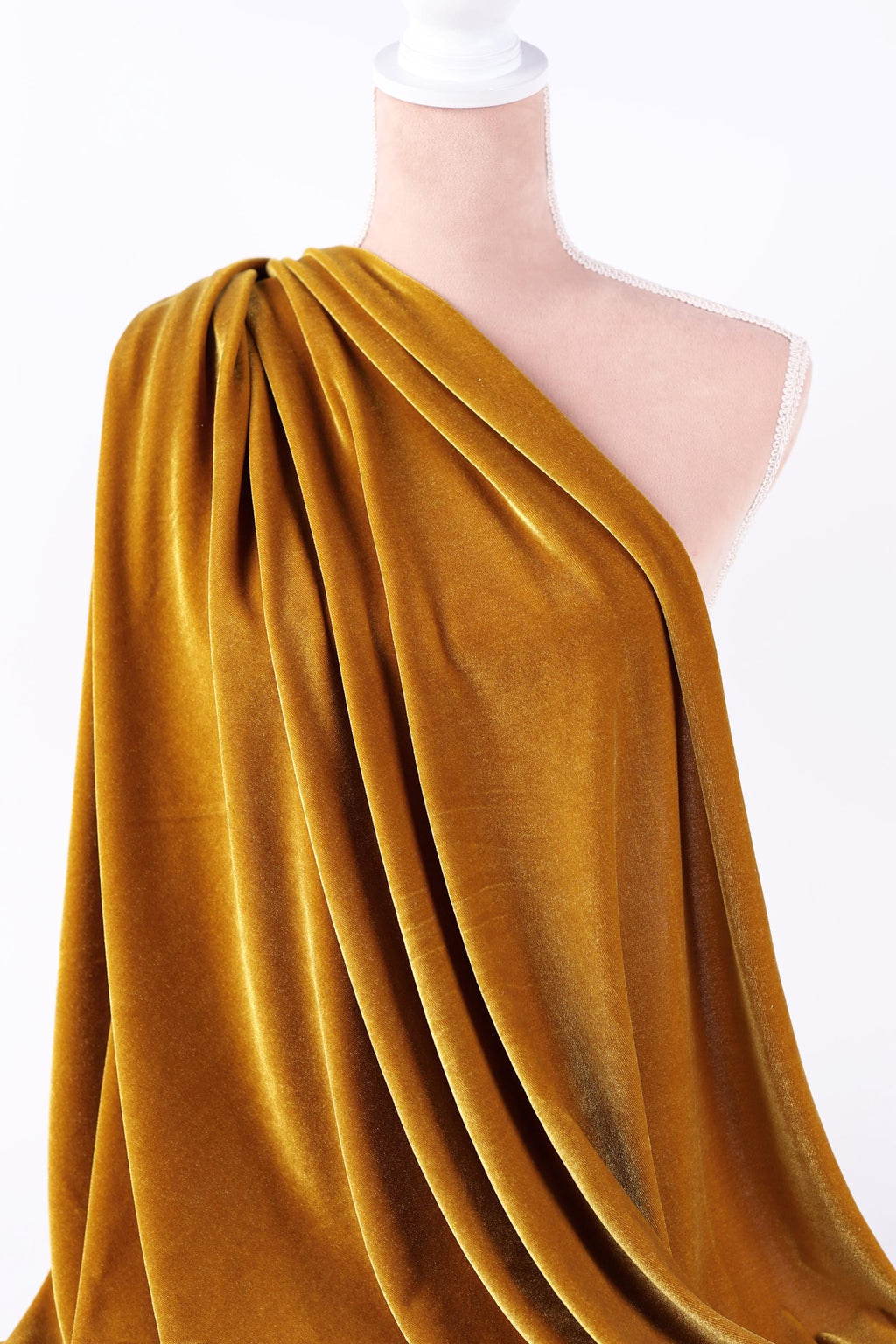 A mannequin wearing a gold velvet fabric draped over its shoulder.