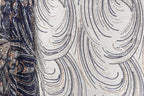 a close-up view of a fabric with a repeating pattern of sequin designs in shades of blue, white, and gold. The pattern consists of curved lines and swirls, creating a visually striking and intricate design.