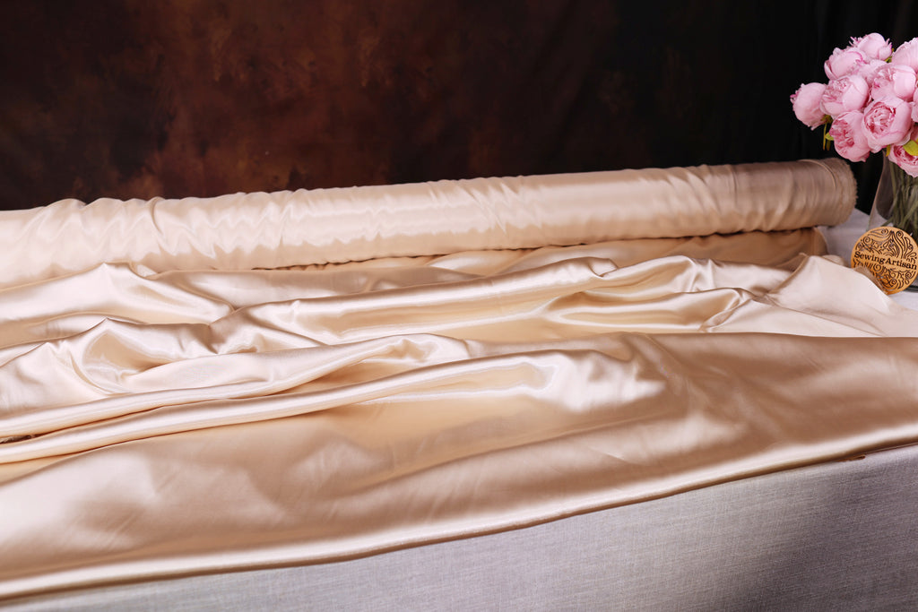 a roll of satin fabric with a floral arrangement of pink flowers placed next to it.