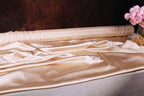 a roll of satin fabric with a floral arrangement of pink flowers placed next to it.