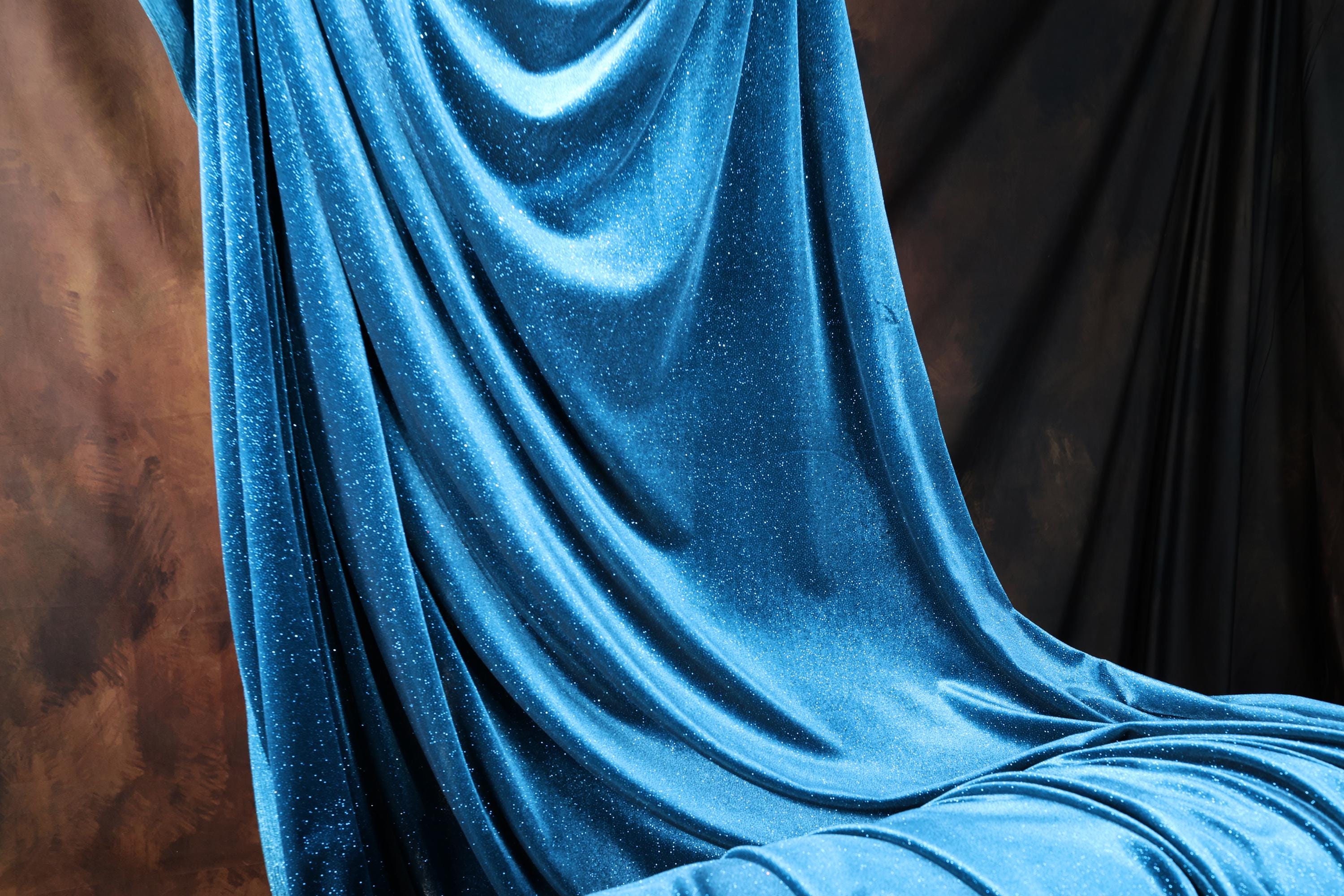 a blue velvet covered bed in a room