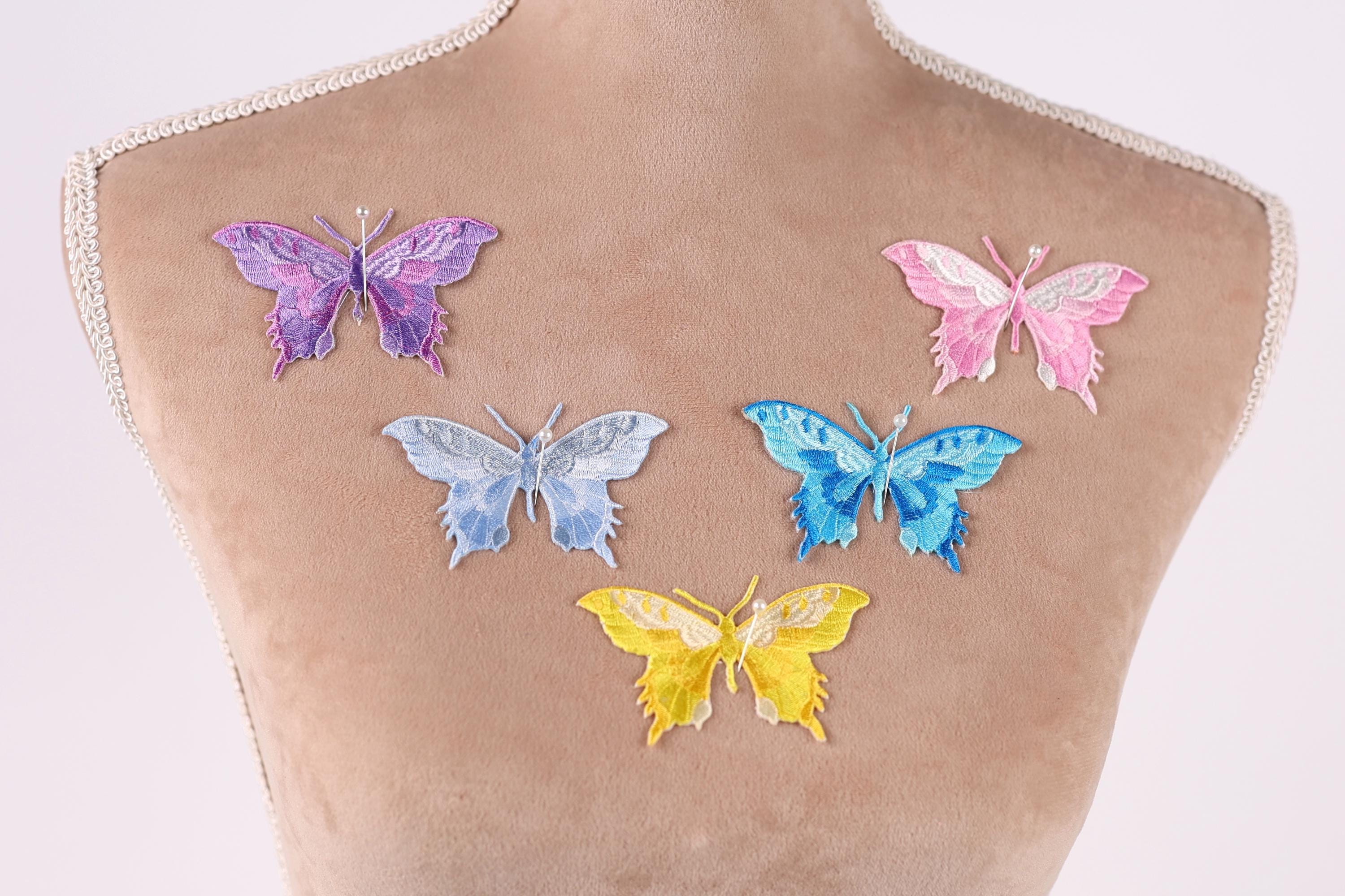 a mannequin torso with six colorful butterfly patches on it, each with a different color and design.