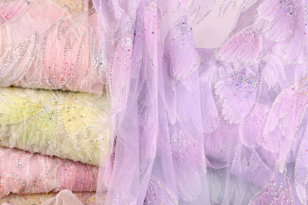 a close-up view of a fabric with a floral pattern in shades of pink and purple. The fabric appears to be made of sheer material, with a delicate and intricate design.