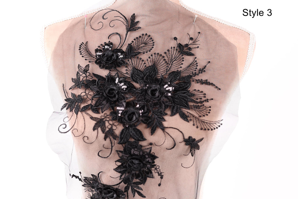 a close-up view of a delicate, intricate black lace design on the back of a dress or garment.