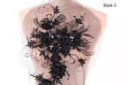 a close-up view of a delicate, intricate black lace design on the back of a dress or garment.