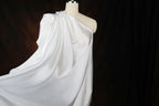 A mannequin wearing a white, flowing garment against a dark background.