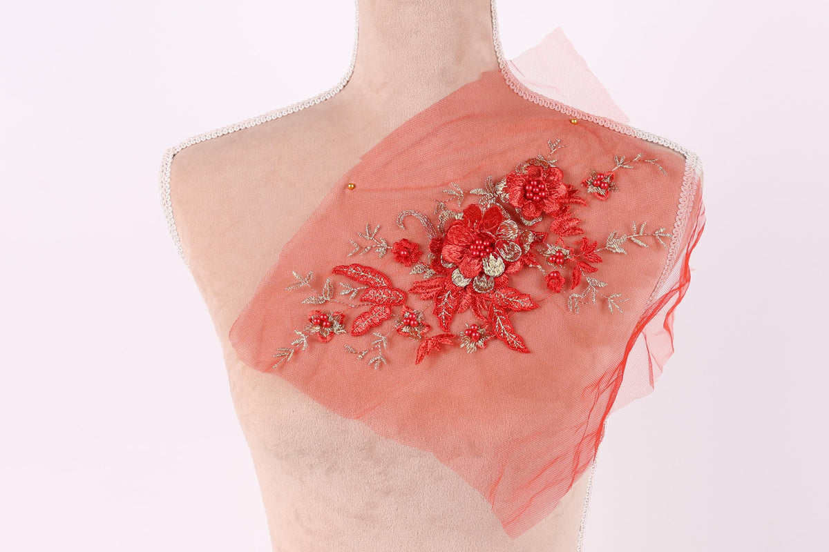 A mannequin torso with a red floral embroidered on it, set against a white background.