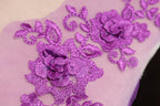 a close-up view of a delicate purple floral embroidery on a fabric surface.