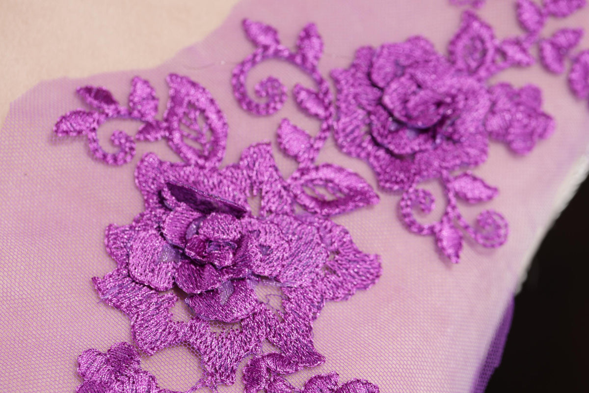 a close-up view of a delicate purple floral embroidery on a fabric surface.