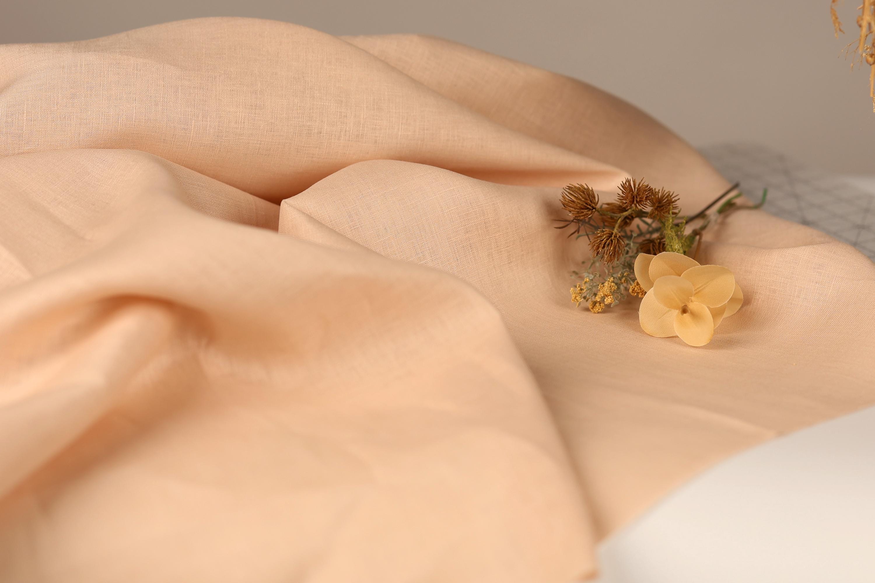 a close-up view of a fabric with a delicate yellow flower resting on it.
