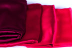 a close-up view of a pile of red and purple fabric, with the red fabric appearing more vibrant and the purple fabric appearing more muted.