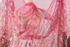 A mannequin wearing a pink and gold sequined dress with a sheer pink and gold fabric draped over it.