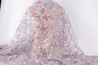 a sheer fabric with a floral pattern, including pink, white, and purple flowers, as well as leaves and other decorative elements. The fabric appears to be a sheer, sheer fabric with a floral design.