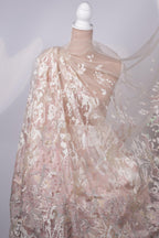 A close-up view of a delicate, lace-like fabric with a floral pattern, featuring a white and pink color scheme.