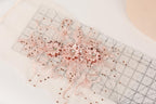 a close-up view of a delicate, intricate piece of lace or fabric adorned with small, sparkling beads or sequins. The lace appears to be embellished with a floral design, adding a touch of elegance and sophistication to the piece. The image is a close-up of the lace, showcasing its intricate details and craftsmanship.