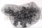 a close-up view of a decorative piece with intricate black and gray floral elements, including leaves and flowers, set against a white background.