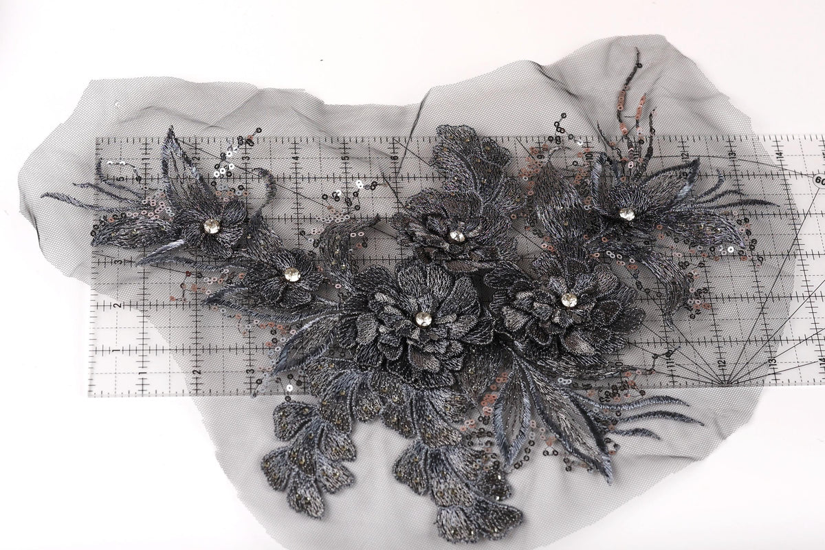 a close-up view of a decorative piece with intricate black and gray floral elements, including leaves and flowers, set against a white background.