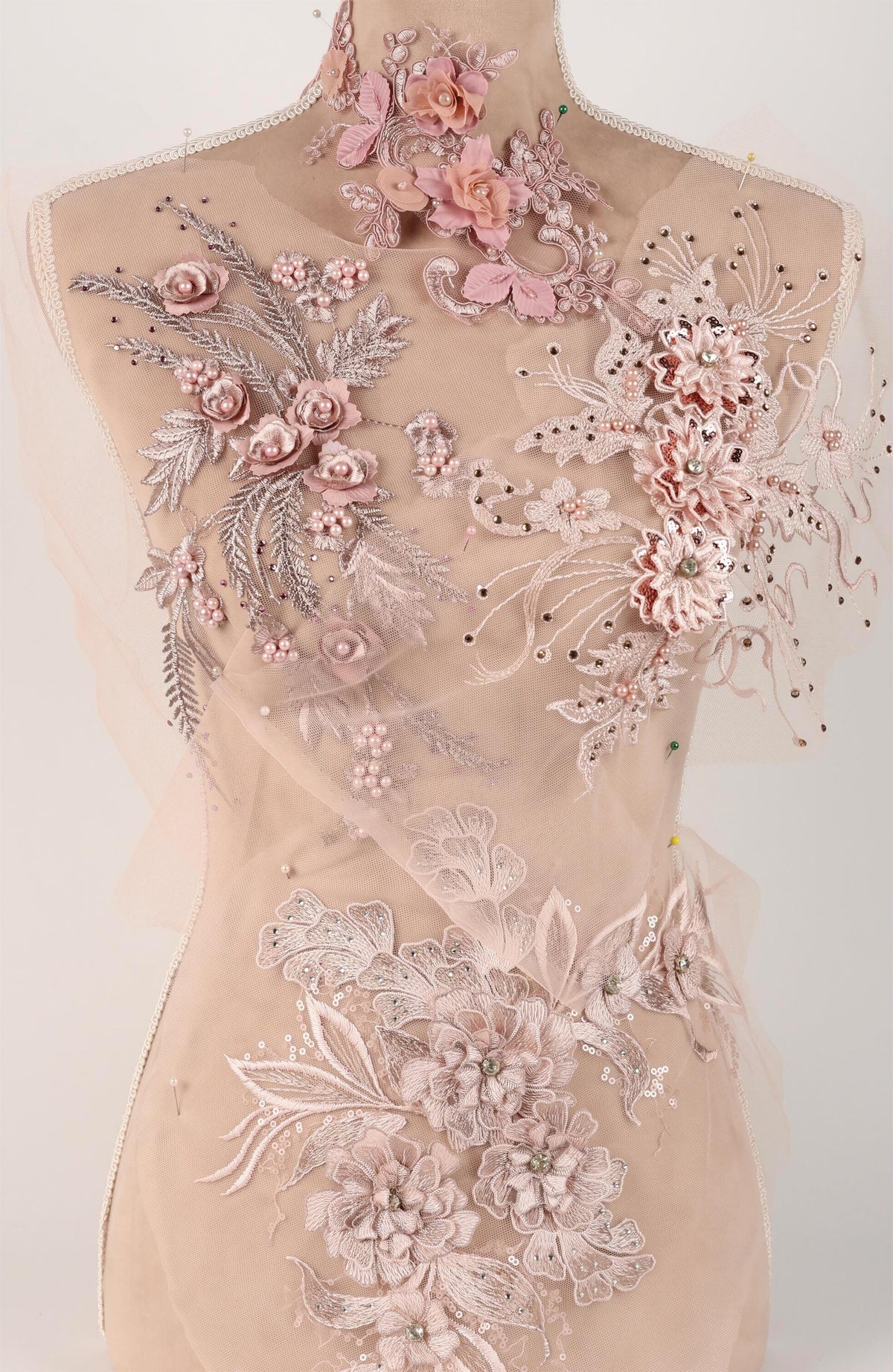 A mannequin wearing a dress with intricate floral embroidery and lace details.