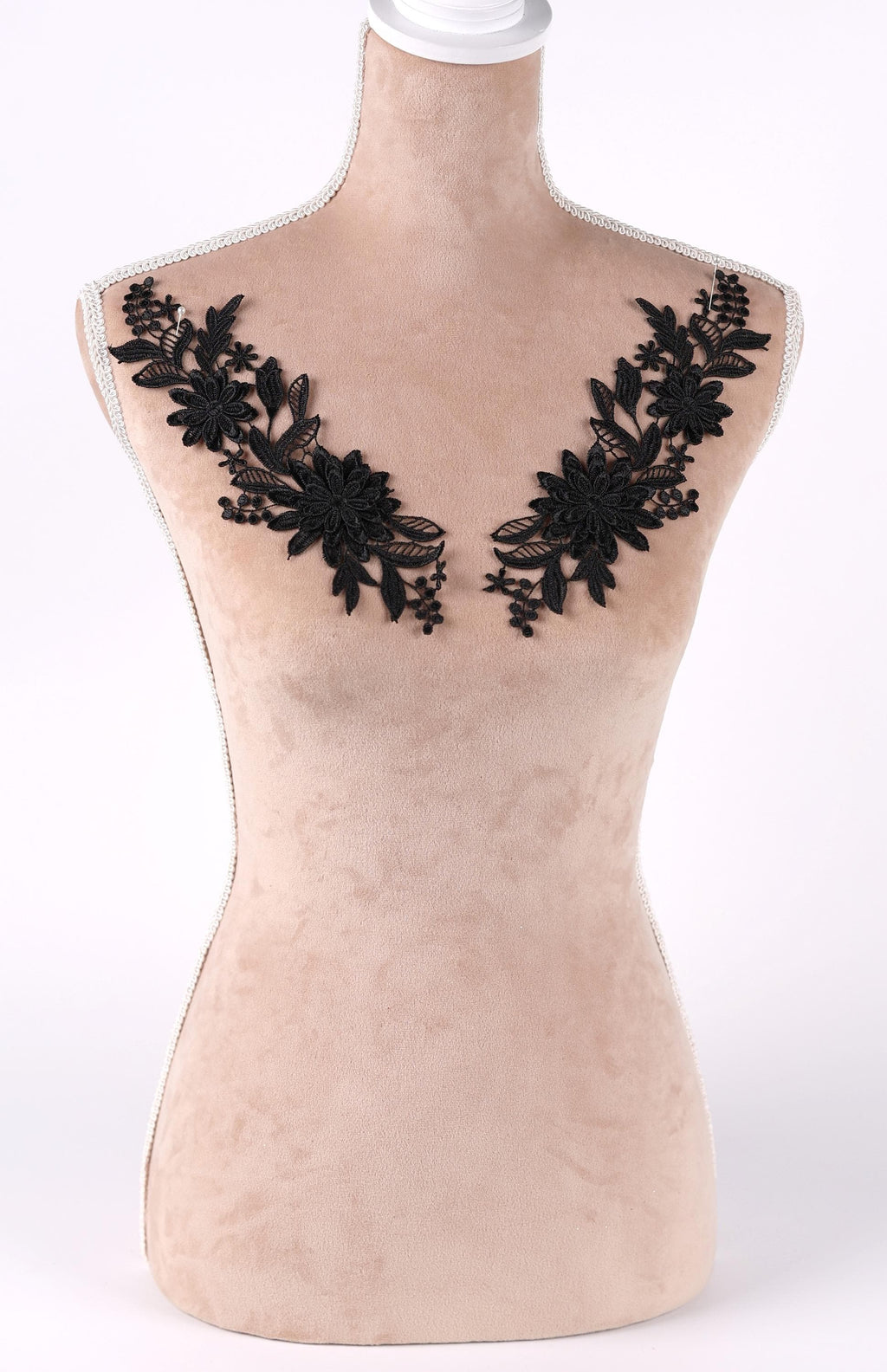 A mannequin with a beige body and black floral embroidery on the bust area.