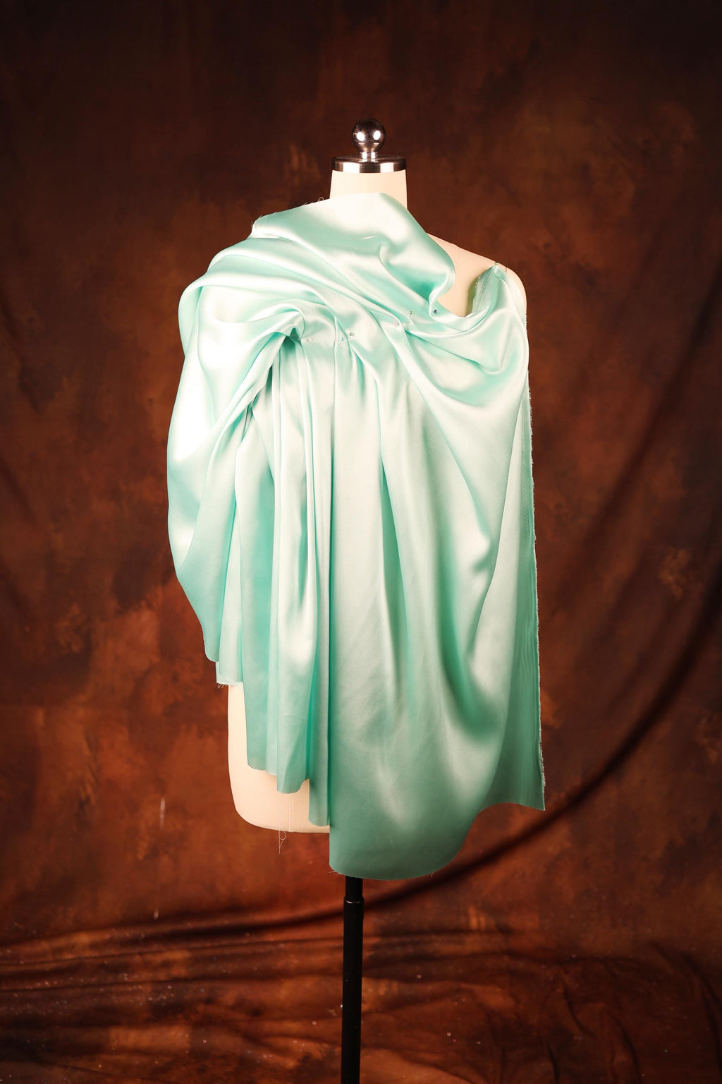 a mannequin wearing a light green draped dress