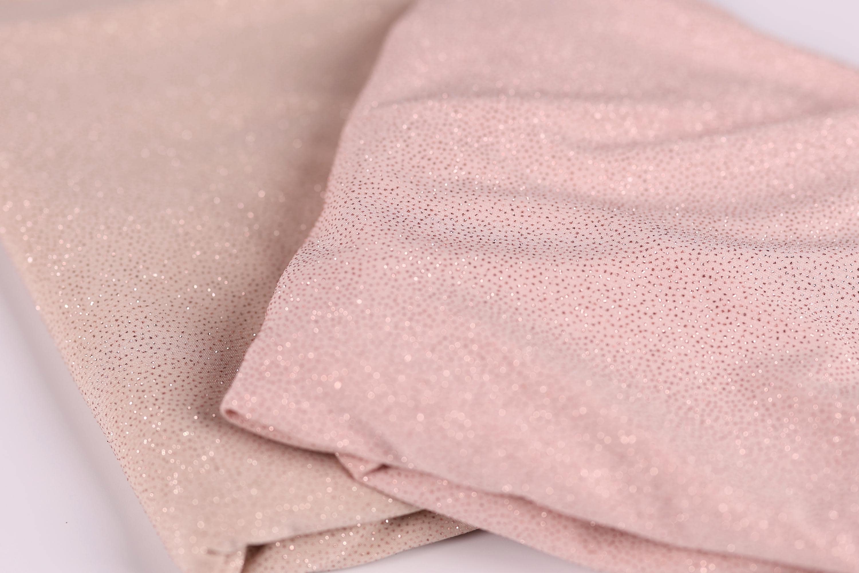 two pieces of fabric, one in a light pink color and the other in a darker pink color, both with a glittery texture.