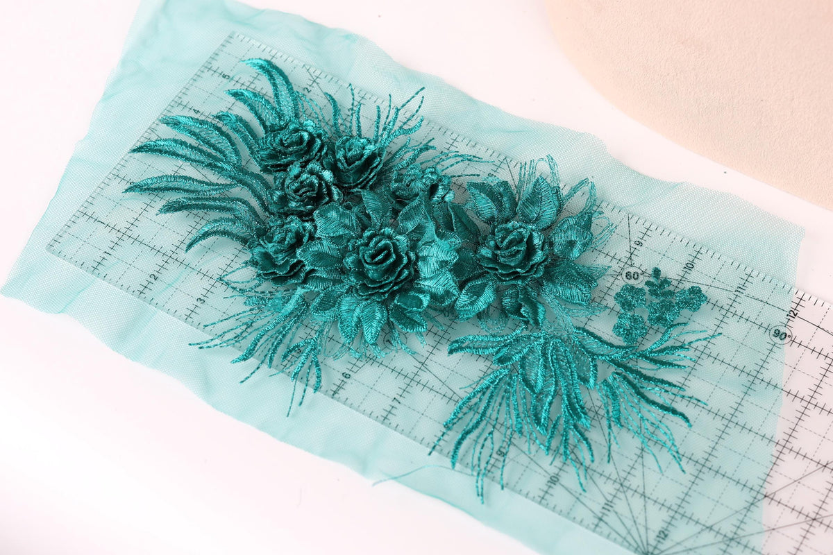 a close-up view of a piece of fabric with a floral design, including green leaves and flowers. The fabric appears to be a light blue color, and there is a ruler visible in the background.
