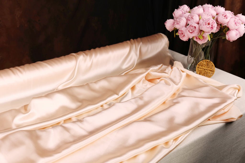 a table with a white tablecloth, a vase of pink flowers, and a gold medal.
