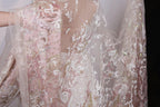 a close-up view of a delicate, lace-like fabric with a floral pattern in shades of pink and white. The fabric appears to be made of sheer material, giving it a delicate and airy appearance.