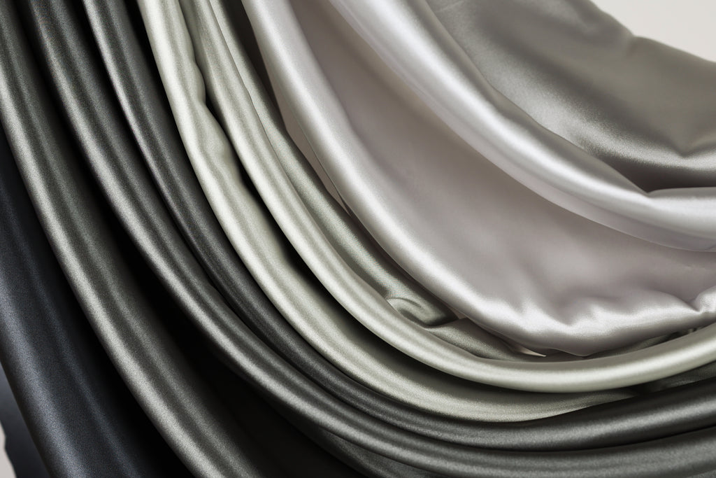 a close-up view of a collection of fabric swatches in various shades of gray and black, arranged in a layered and cascading manner.