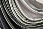 a close-up view of a collection of fabric swatches in various shades of gray and black, arranged in a layered and cascading manner.