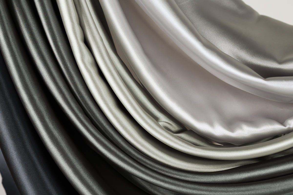 a close-up view of a collection of fabric swatches in various shades of gray and black, arranged in a layered and cascading manner.