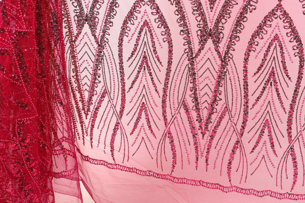 a close-up view of a fabric with a pink and red pattern, featuring a repeating design of leaves and flowers. The fabric appears to be made of a sheer material, with a delicate and intricate design.