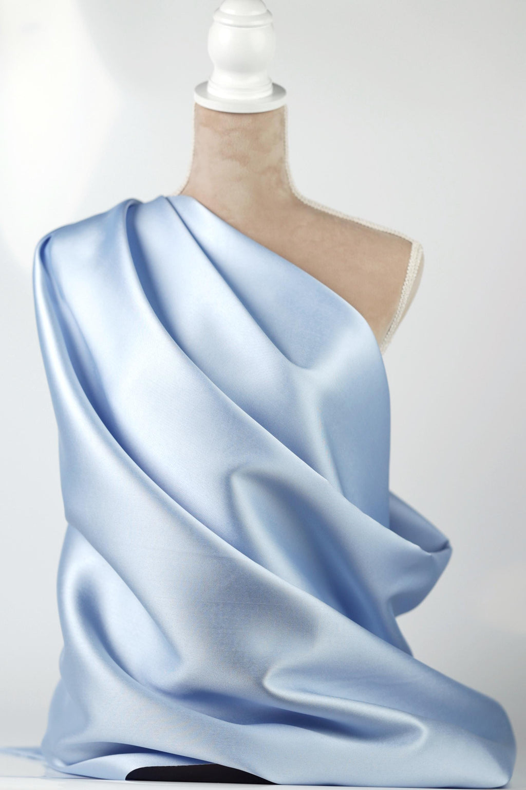 A mannequin wearing a blue satin fabric draped over its body.