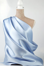 A mannequin wearing a blue satin fabric draped over its body.