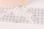 a close-up view of a delicate white lace piece, possibly a veil or a decorative element, placed on a ruler for measurement purposes.