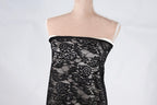 A mannequin wearing a black lace dress with a floral pattern.