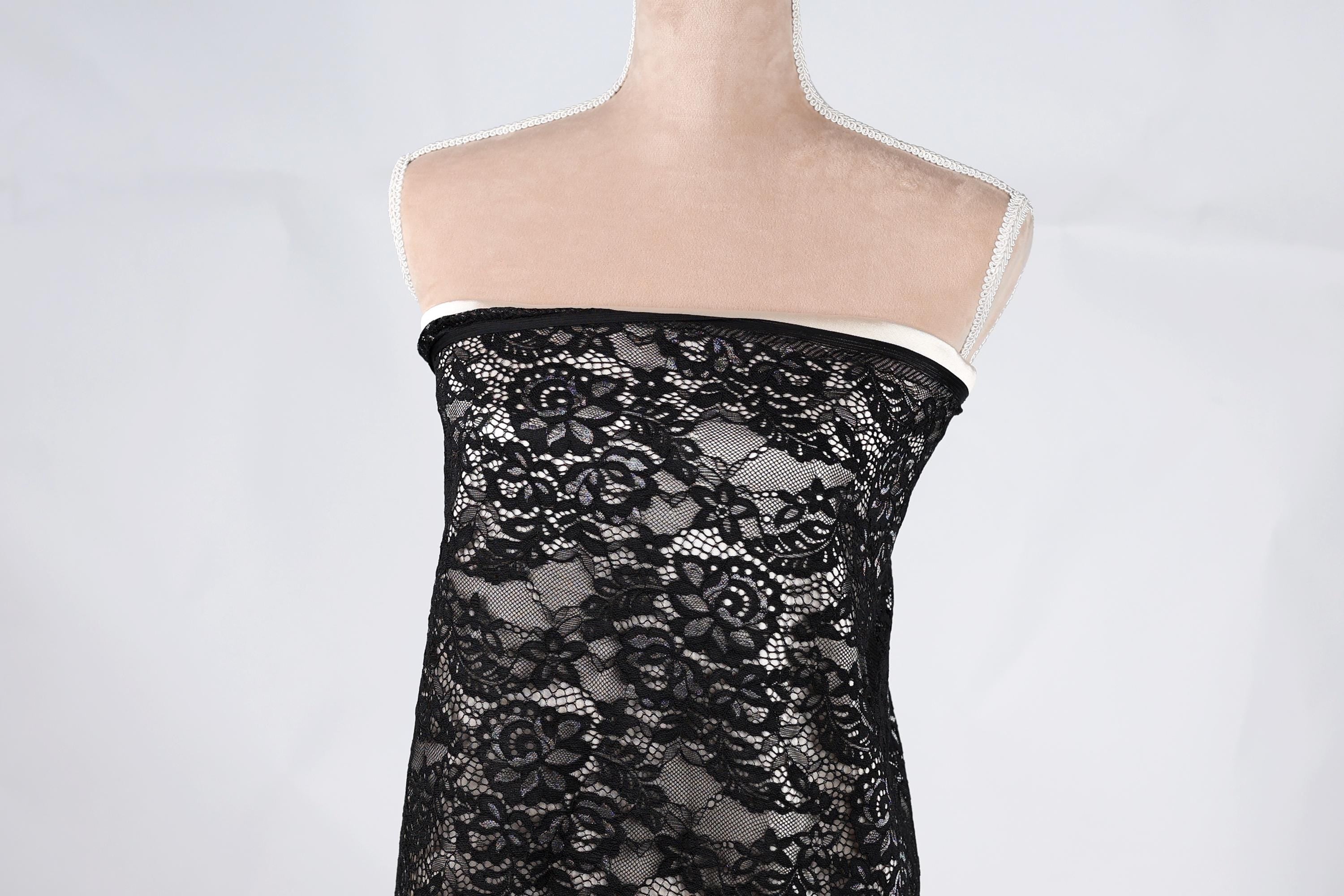 A mannequin wearing a black lace dress with a floral pattern.