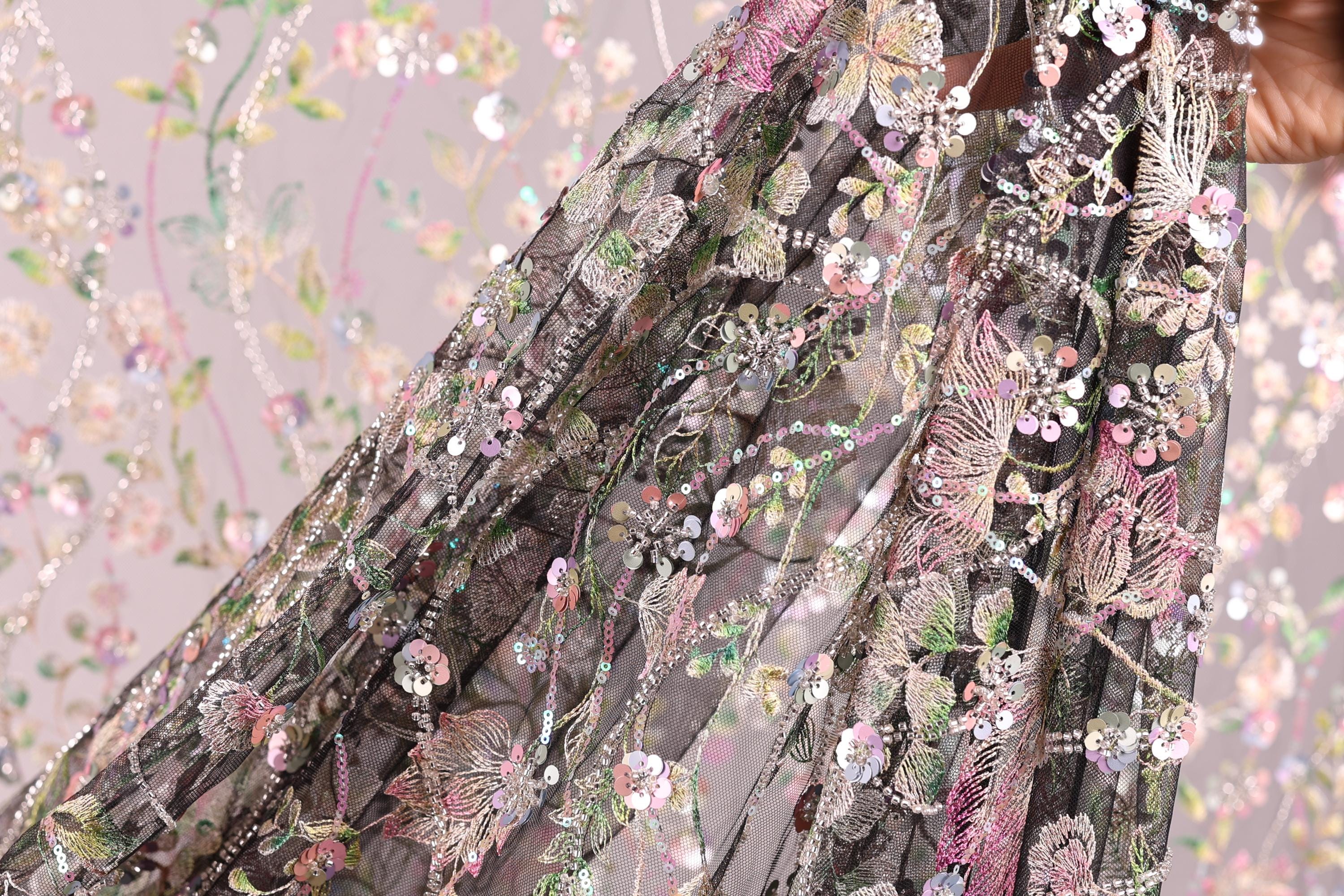 a close-up view of a delicate, intricately embroidered fabric with a floral pattern. The fabric appears to be a sheer, sheer lace or chiffon, with a variety of colorful flowers and leaves adorning the surface. The image is a close-up of the fabric, showcasing the detailed craftsmanship and the vibrant colors of the floral design.