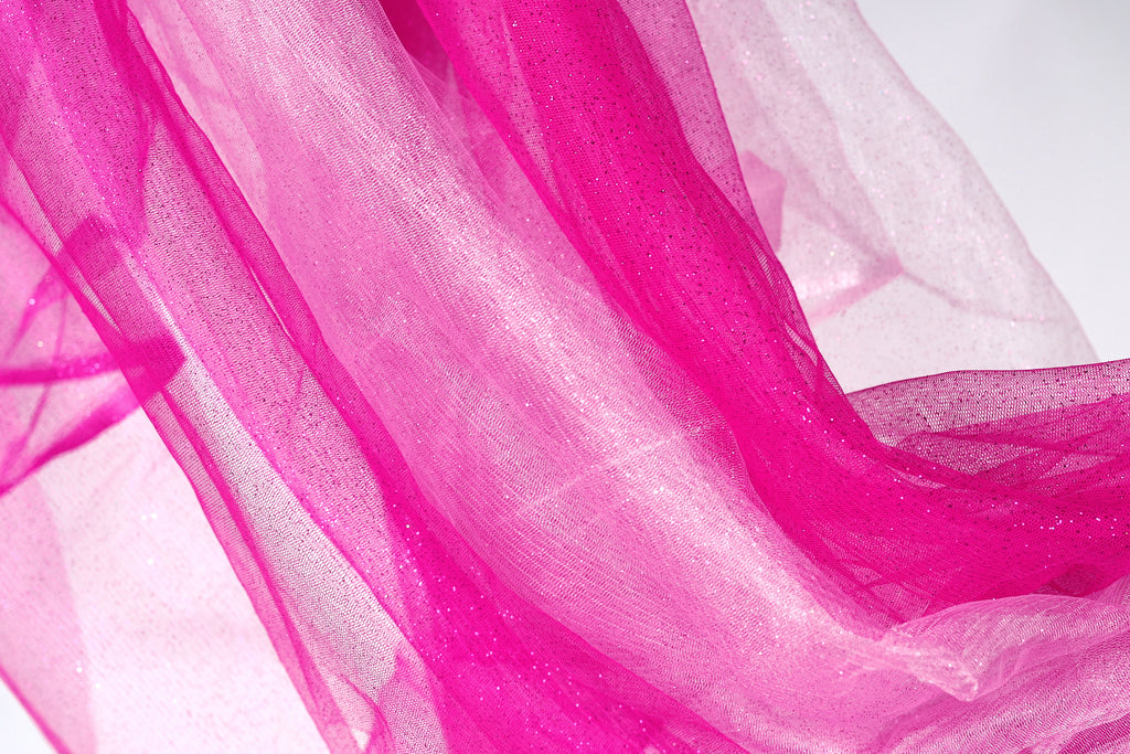 a close-up view of a fabric with a pink and white color scheme, featuring a shiny, sparkly texture.