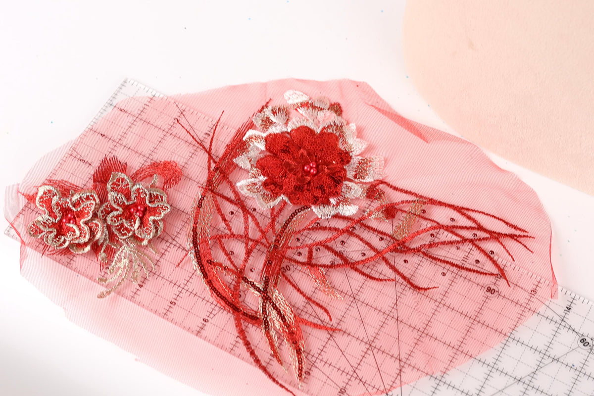 a pink fabric with red and white floral designs, including a large red flower and smaller red flowers, as well as some red and white decorative elements.