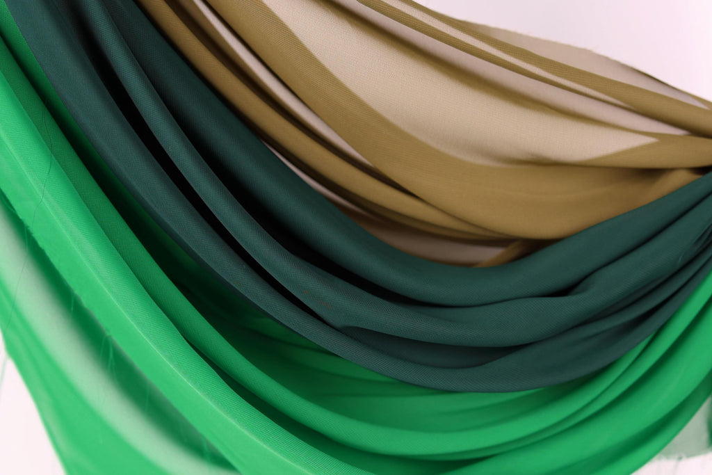 a close-up view of a collection of colorful fabric swatches, including shades of green, brown, and beige.
