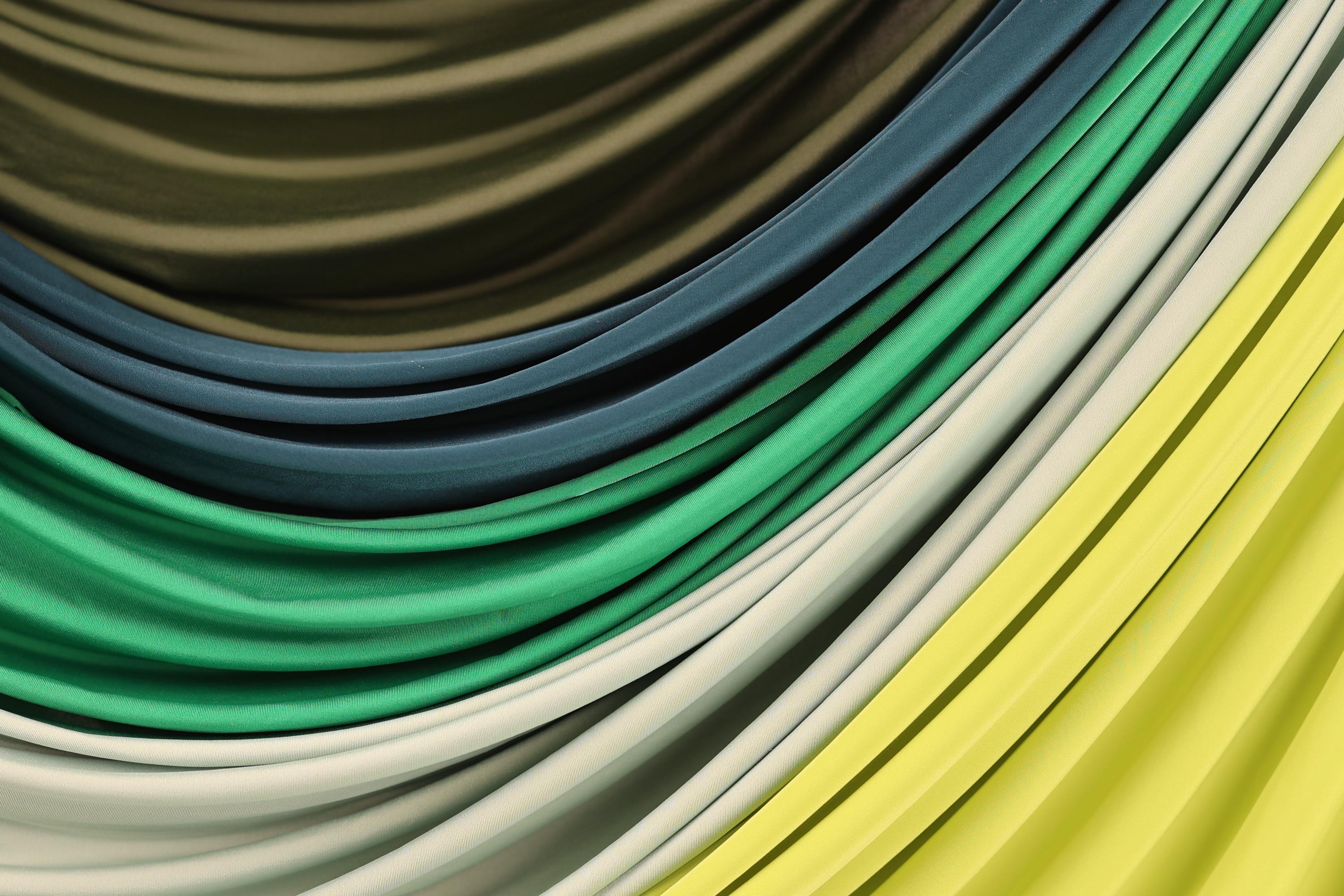 a close-up view of a variety of colorful fabrics, including green, blue, yellow, and white, arranged in a visually appealing manner.