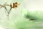a glass vase with flowers and a green fabric draped over a table, creating a serene and elegant atmosphere.