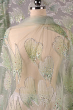 a close-up view of a fabric with a delicate, intricate design of green and white hearts and leaves. The fabric appears to be a sheer material, with the hearts and leaves appearing as if they are attached to the fabric using a sewing technique. The background of the image is a light green color, which complements the color scheme of the hearts and leaves.