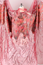 a pink and red fabric with a floral pattern, hanging on a mannequin.