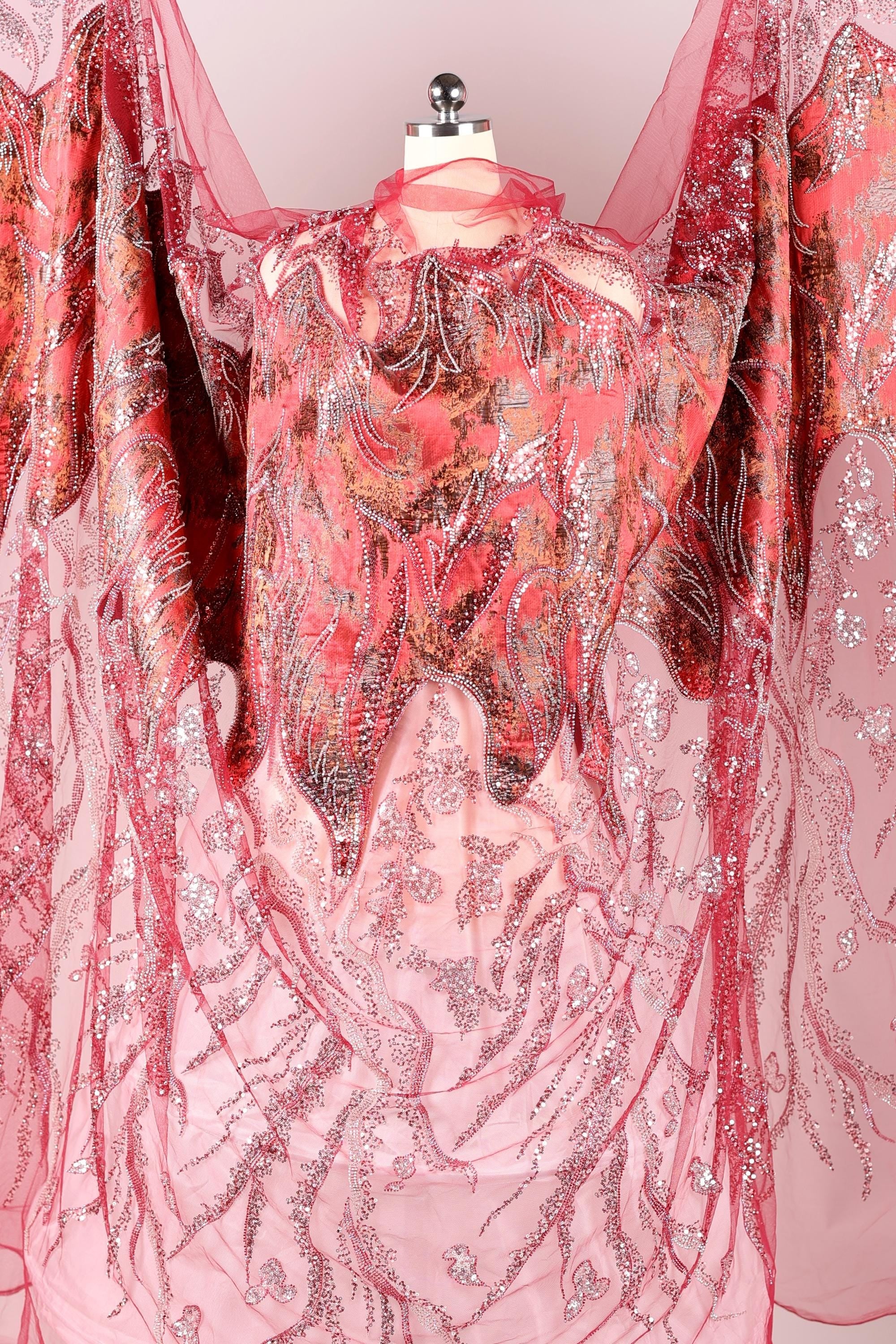 a pink and red fabric with a floral pattern, hanging on a mannequin.